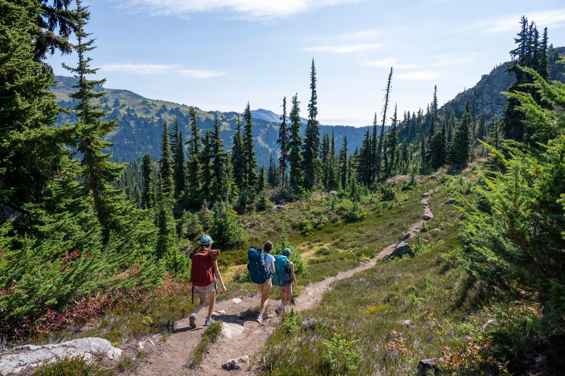 Mother and daughters backpack on mountain trail